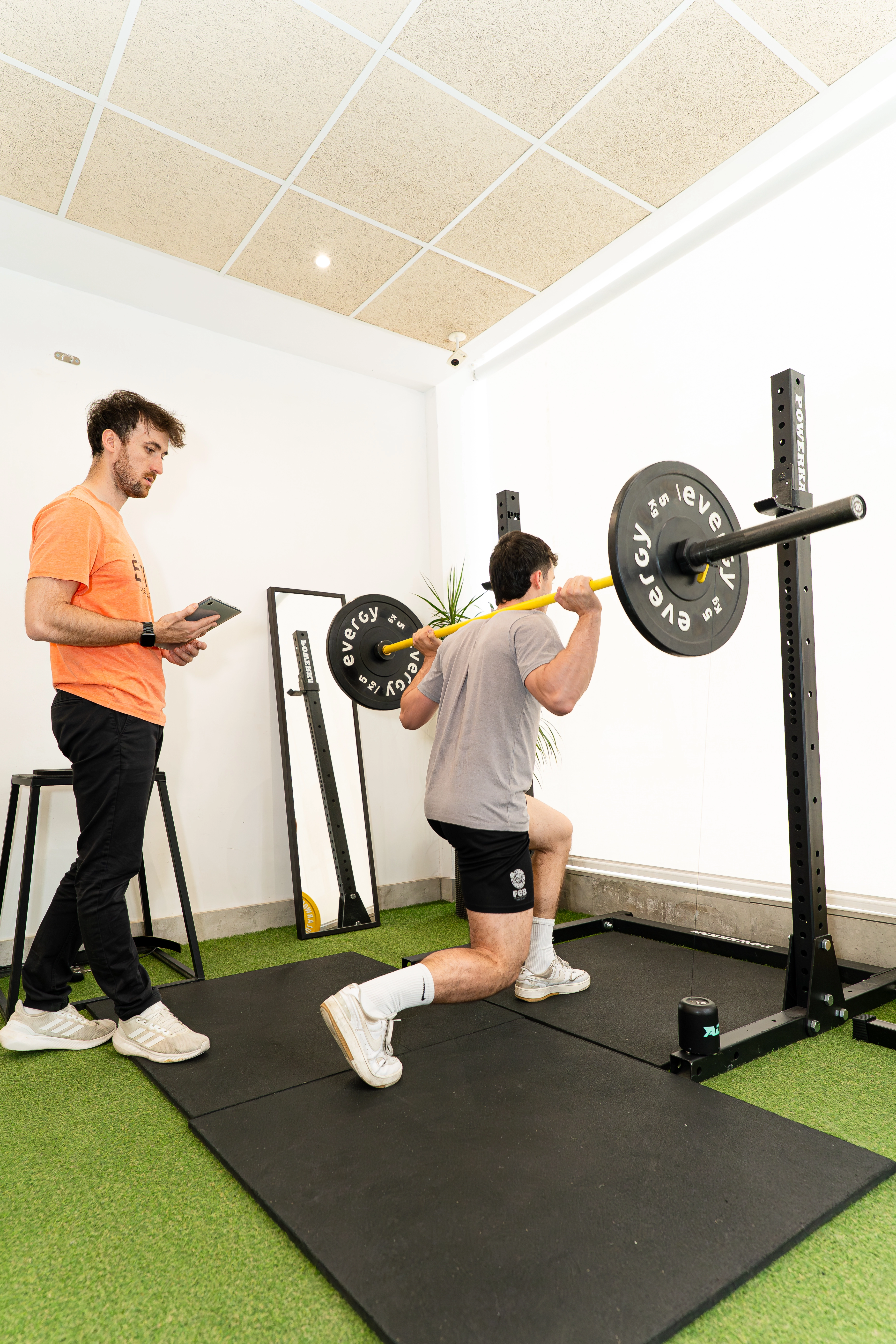 Paciente realiza zancada con barra guiado por fisioterapeuta en sesión del programa É-Activos