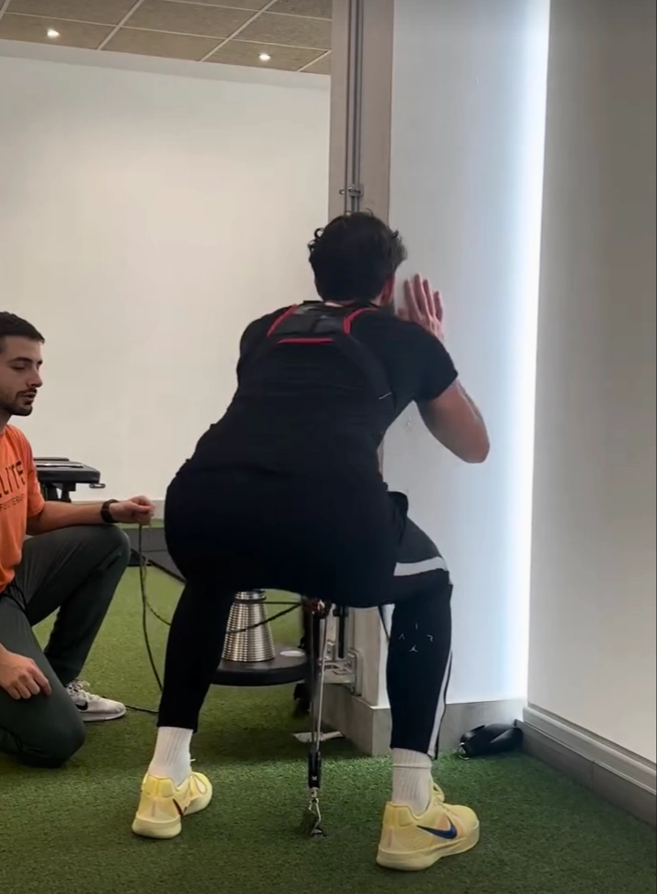 Paciente realiza sentadilla con resistencia bajo supervisión en programa É-Activos de Élite Fisioterapia
