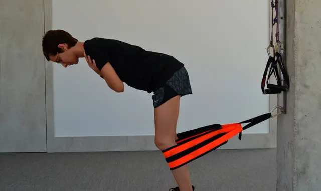 Mujer realizando trabajo excéntrico para glúteos con resistencia elástica