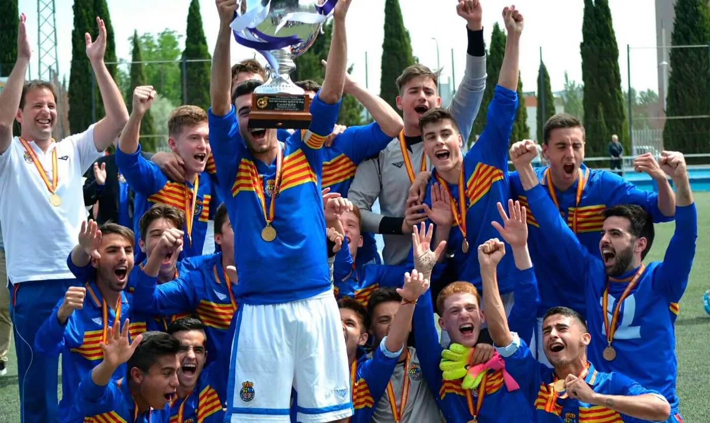 Equipo de fútbol juvenil celebrando con trofeo de campeonato